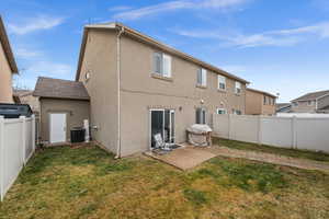 Back of property with a fenced backyard, stucco siding, and a patio area
