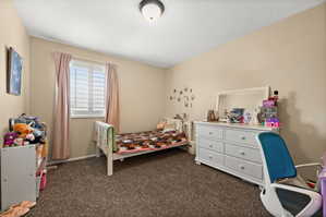 Bedroom with dark colored carpet and baseboards