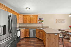 Kitchen featuring stainless steel appliances, a peninsula, a kitchen bar, open shelves, and dark wood-type flooring