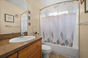 Full bathroom with vanity, shower / bathtub combination with curtain, and light tile patterned floors