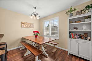 Dining space with dark wood-style flooring and a chandelier