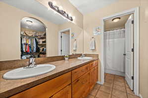 Bathroom with double vanity, a spacious closet, and light tile patterned flooring