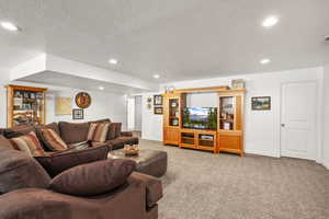 Carpeted living area featuring recessed lighting and a textured ceiling