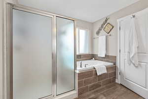 Full bath featuring a stall shower, a garden tub, and wood tiled floors