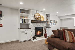 Living room featuring a textured ceiling, a fireplace, light colored carpet, and recessed lighting