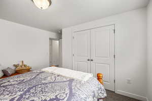 Carpeted bedroom featuring a closet and baseboards
