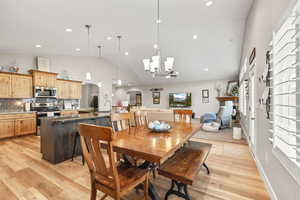 Dining space featuring arched walkways, suspended lighting, light wood-type flooring, and lofted ceiling