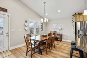 Dining space with lofted ceiling, light wood-style floors, and a chandelier