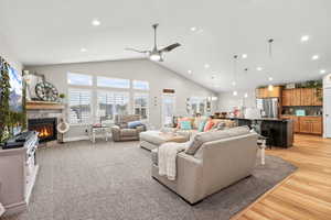 Living room featuring a tile fireplace, ceiling fan, a high ceiling, and suspended lighting