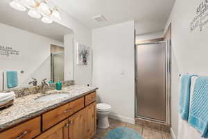 Bathroom with vanity, a shower stall, light tile patterned flooring, and suspended lighting