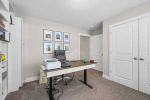 Office area featuring dark carpet and baseboards
