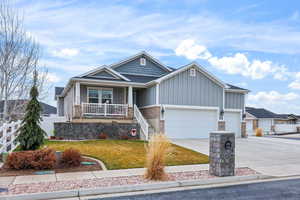 Craftsman house with board and batten siding, a porch, driveway, and an attached garage