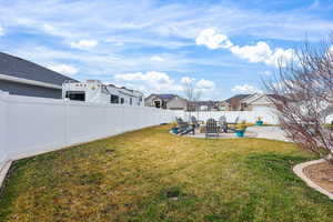 Fenced backyard with a residential view, a patio area, and an outdoor fire pit