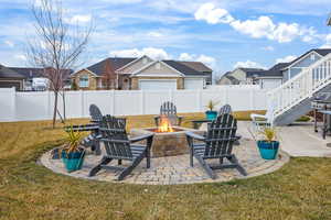 Fenced backyard featuring a patio, a fire pit, a residential view, and a grill
