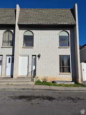 French country style house featuring brick siding and a shingled roof