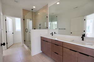Primary Bathroom with double vanity, a shower stall, recessed lighting, and light tile patterned floors
