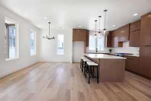 Kitchen with suspended lighting, modern cabinets, a kitchen bar, light wood-type flooring, and a kitchen island