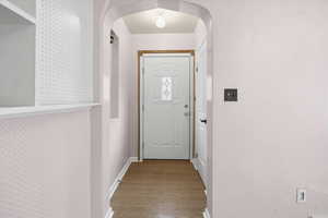 Entryway with arched walkways and wood finished floors