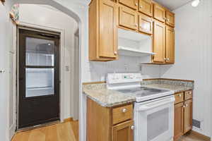 Kitchen featuring white electric range, light wood-style flooring, light stone counters, and open shelves