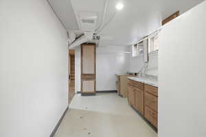 Bar with wood finish cabinets, light countertops, finished concrete flooring, and freestanding refrigerator