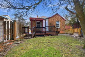 Back of house with a fenced backyard, a chimney, a wooden deck, and brick siding