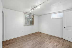 Basement featuring track lighting and light wood finished floors