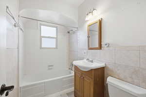 Bathroom with tile walls, vanity, and shower / bathtub combination