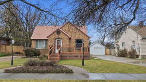 View of front of home featuring brick siding, a garage, a deck, concrete driveway, and an outdoor structure