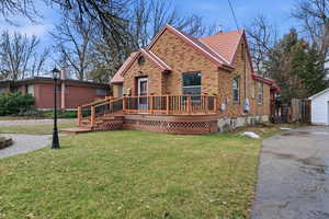 View of front of house with brick siding, a wooden deck, and a front lawn