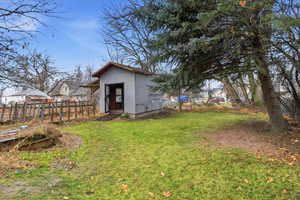Fenced backyard featuring an outbuilding