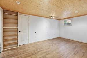 Unfurnished room with wood ceiling, light wood-style flooring, crown molding, and a smoke detector