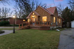 View of front of house featuring brick siding, a front yard, and a wooden deck