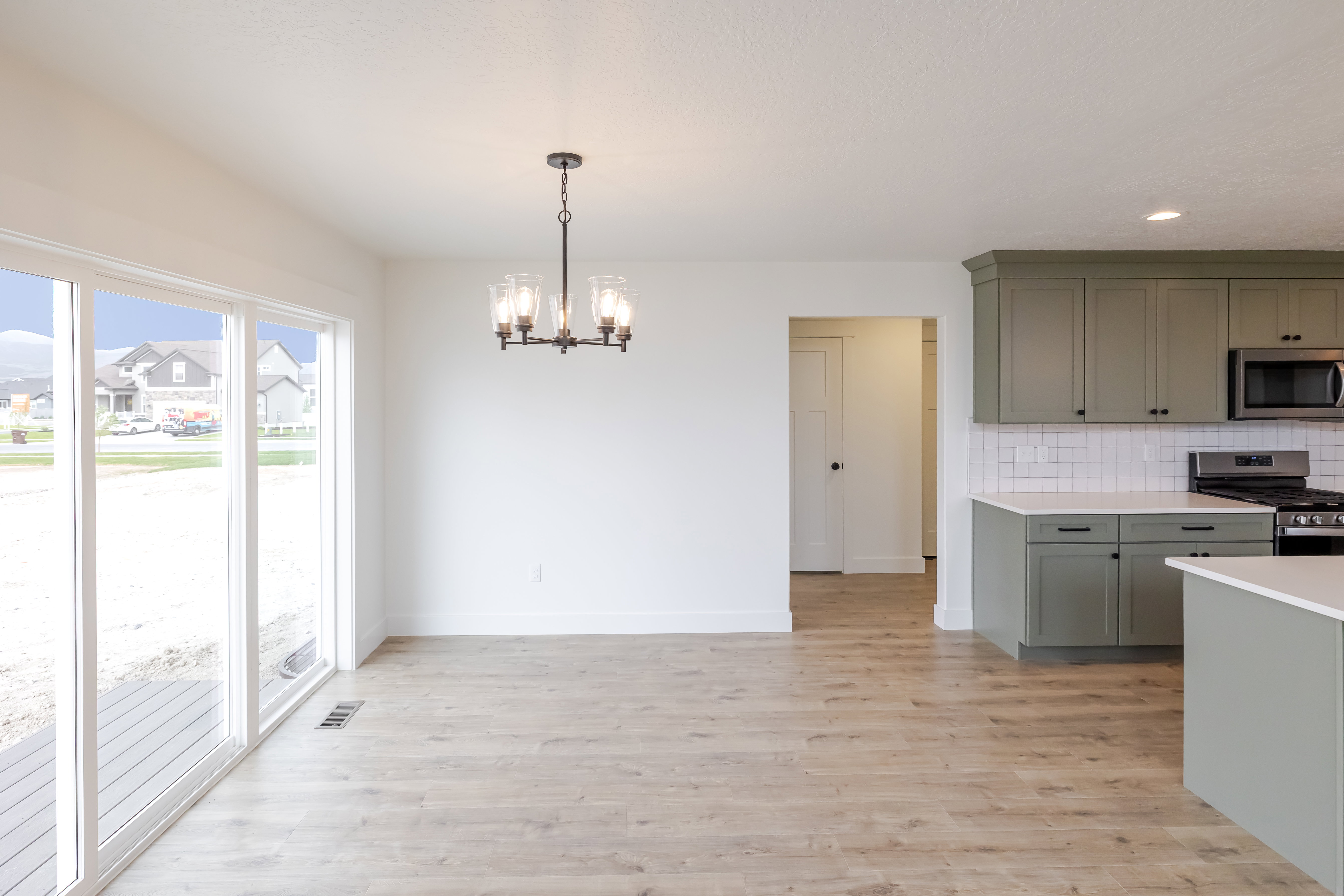 Open-concept living space featuring wood-finish flooring, a contemporary chandelier, and large sliding glass doors