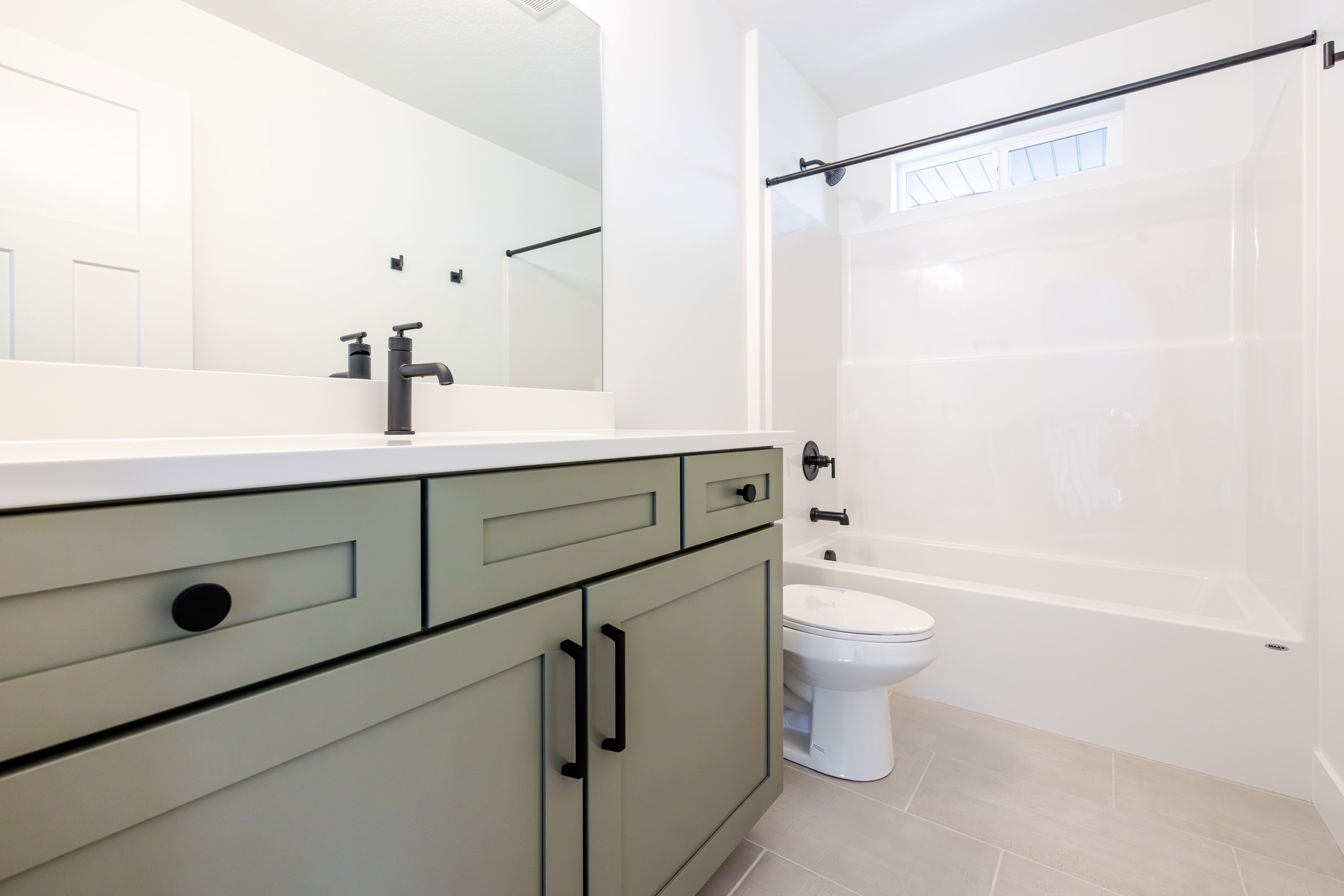 Modern bath featuring a sage green vanity with matte black hardware, white countertop, and a sleek black faucet