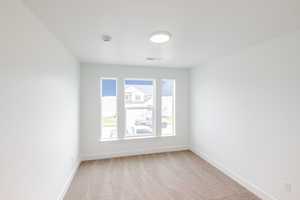 Bright interior space featuring three large windows, neutral-toned carpeting, white walls, and a ceiling-mounted light fixture
