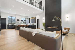 Living area featuring a large fireplace, light wood finished floors, a high ceiling, and recessed lighting