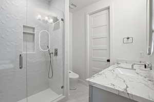 Bathroom with vanity and a marble finish shower