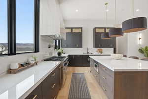 Kitchen featuring modern cabinets, pendant lighting, double oven range, two tone cabinetry, and light stone counters