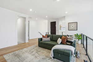 Living area with light wood-type flooring and recessed lighting