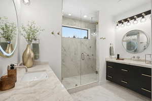Bathroom with two vanities, a marble finish shower, and recessed lighting