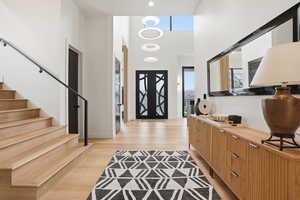 Entrance foyer with light wood-style flooring and a high ceiling