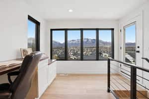 Office with light wood-style flooring, a mountain view, and recessed lighting