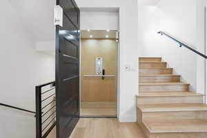 Staircase with wood finished floors and elevator
