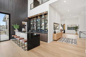 Indoor wet bar featuring modern cabinets, a high ceiling, recessed lighting, and dark stone counters