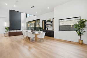 Dining area featuring a high ceiling, light wood finished floors, a fireplace, and recessed lighting