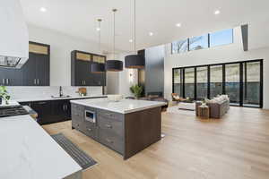 Kitchen featuring light stone counters, a breakfast bar, modern cabinets, a kitchen island, and pendant lighting