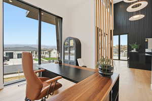 Office area featuring light wood finished floors, a residential view, floor to ceiling windows, and a high ceiling