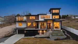 Back of property featuring a balcony, driveway, an attached garage, and a standing seam roof
