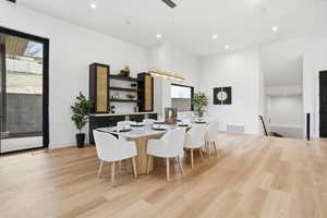 Dining space with light wood-style floors, recessed lighting, and a high ceiling