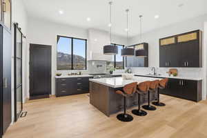 Kitchen featuring a kitchen bar, decorative backsplash, a center island, and hanging light fixtures